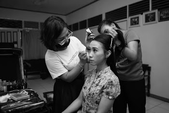 Black-and-White Photo Of A Woman Sitting On Chair Beside Two Woman Doing Her Hair And Makeup