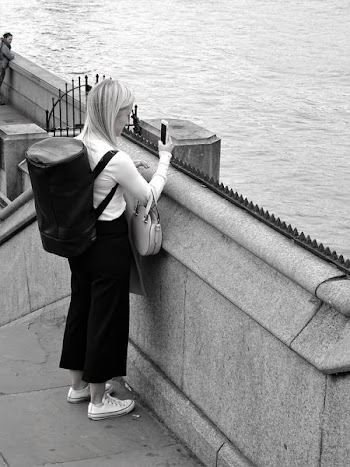 Black and White Photo of Woman Holding Smartphone While Standing Near Calm Water
