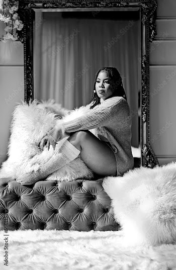 Black and white picture of a black woman sitting on a bench in front of the mirror