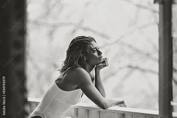 Black and White picture of Black woman on patio smiling about the day