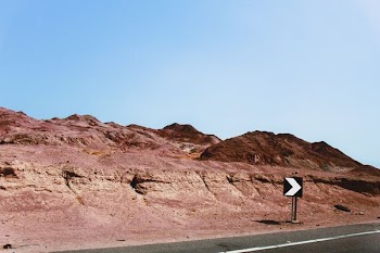 black and white traffic signage near mountains