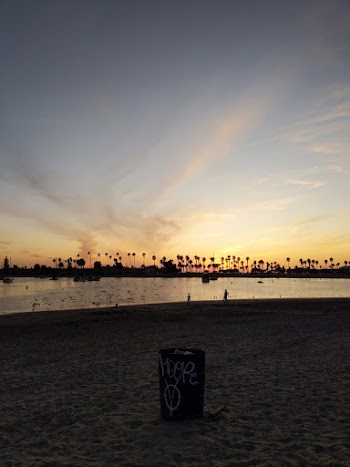 Black and White Trash Bin on Seashore Under Blue and Orange Skies
