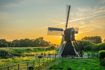 Black and White Wind Mill in Green Field Under Yellow Skies