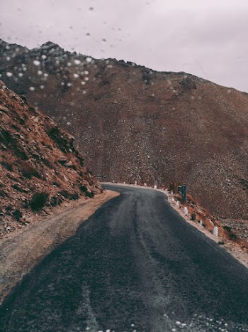 Black Asphalt Road Beside Brown Rock Formation