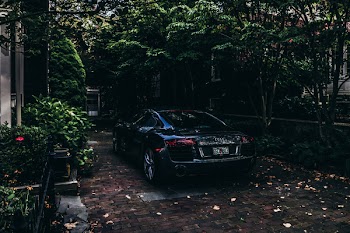 Black Audi Sedan Parked on Pavement Near Trees