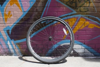 Black Bike Wheel Leaning on Wall