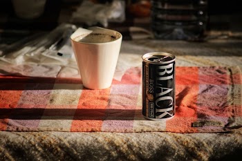 Black Boss Can on Top Beside White Mug