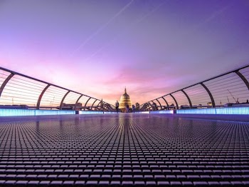 black bridge towards brown building during sunset