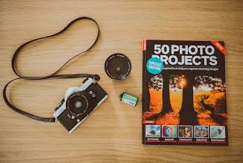 Black Camera And Book On Brown Wooden Surface