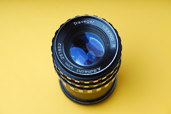 Black camera lens against a yellow background