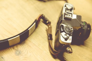 Black Camera With White and Black Strap on Beige Surface