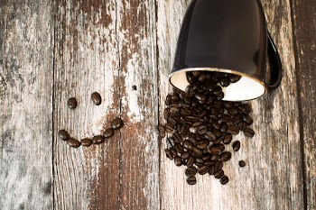 Black Ceramic Cup With Coffee Beans All on Brown Wooden Surface
