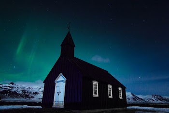 black church under northern lights at nighttime