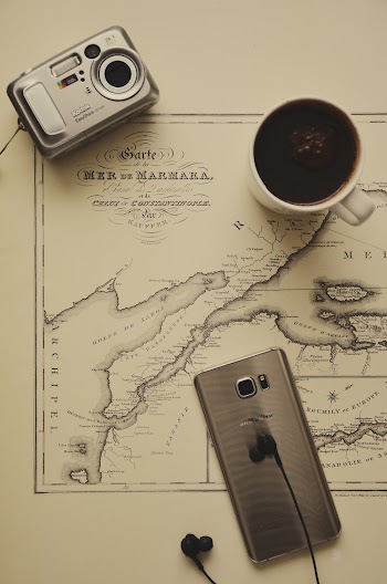 Black Coffee in Mug Near Silver Camera, Gold Smartphone, and Black Earbuds