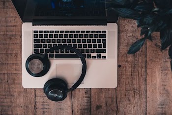 black cordless Bluetooth headphones on top of MacBook Pro