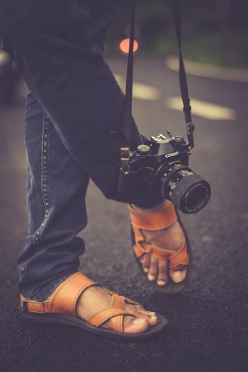 Black Cosina Slr Camera Hanging Beside Foot during Daytime