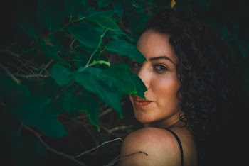 Black Curly Haired Woman Besides Green-leafed Plants