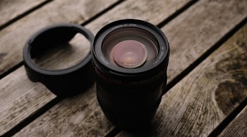 Black Dslr Camera Lens With Lid on Wooden Platform