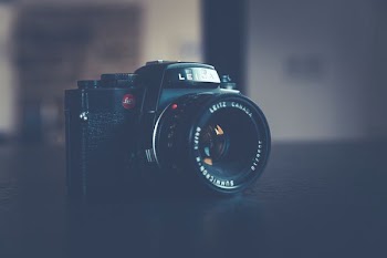 black DSLR camera on top of black wooden table inside white room