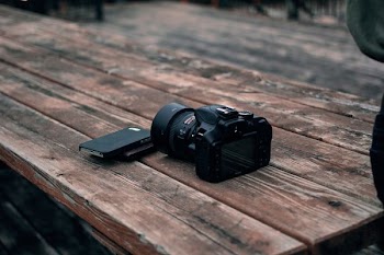 black DSLR camera on top of brown wooden table