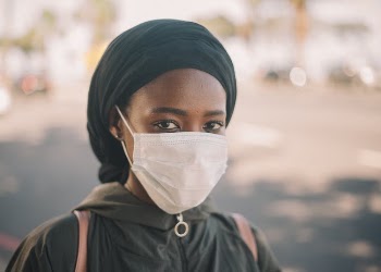 Black female in medical mask on street