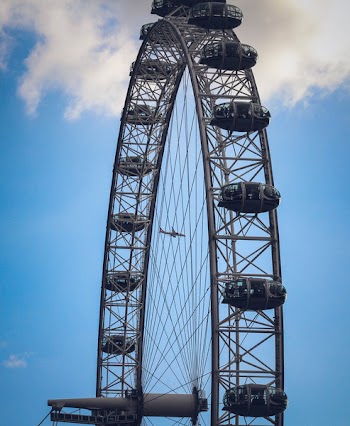 Black Ferris Wheel Under Airplane and White Clouds