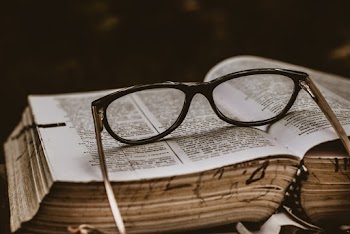 Black Framed Eyeglasses on Top of Open Book