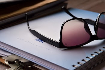 Black Framed Sunglasses on White Spiral Notebook