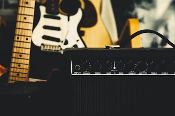 black guitar amplifier beside electric guitar