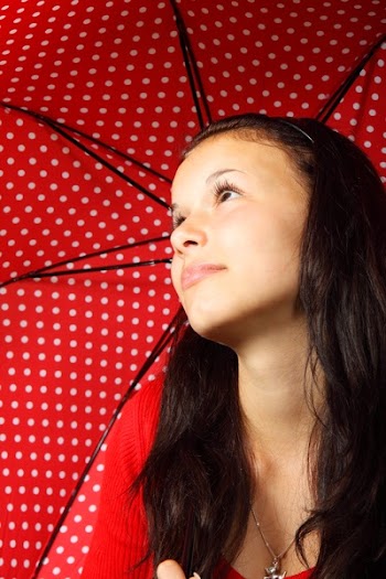 Black Haired Woman in Red Sweater Wearing Silver Dog Pendant Necklace Holding Black Red White Polka Dotted Umbrella