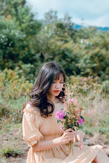 Black-haired Woman Wearing Yellow and White Checkered Off-shoulder Dress Holding Purple and Pink Flowers