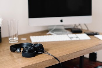 black headphones near Apple keyboard and iMac