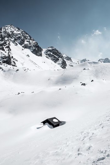 black house in middle of glacier mountain during daytime