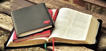 Black Leather Notebook With Red Arrow on Cover on Red Bookm and Bible
