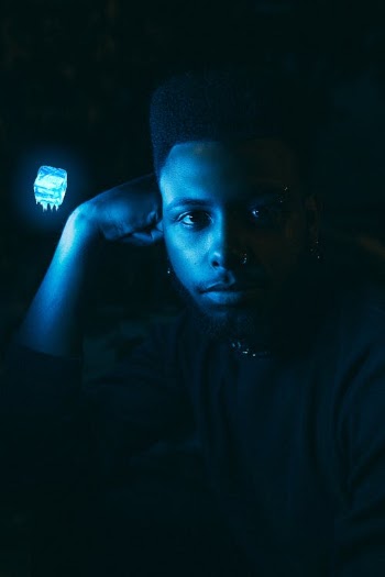 Black man sitting in dark room and looking at camera · Free Stock Photo