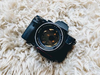 black milc camera on white fur cloth