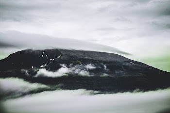 black mountain covered with clouds during daytime