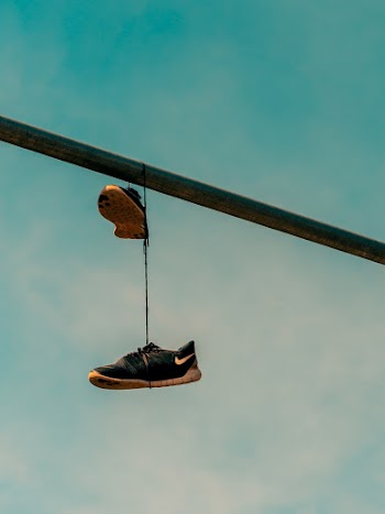 Black Nike Sneakers Hanged on Gray Metal Bar