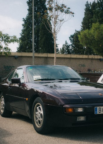 Black Porsche Coupe Near Concrete Wall and Trees