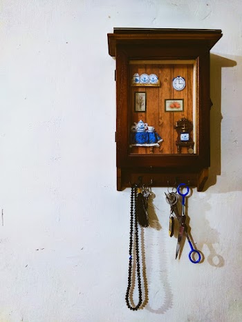 Black Prayer Beads and Blue Scissors Hanging on Wall Hook