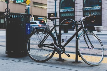 black rigid mountain bicycle parked next to black trash bin