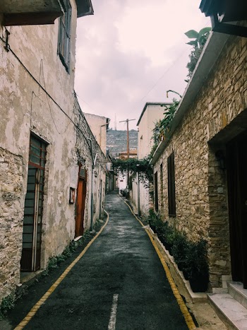 Black Road in Between Beige Walls Under Cloudy Sky