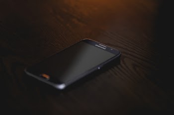 Black Samsung Smartphone at Brown Wooden Surface
