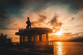 Black Statue on Top of White Building Across Sunset