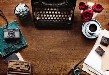 black typewriter near gray camera on brown wooden surface