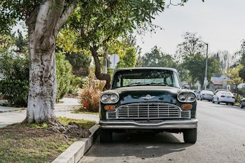 black vehicle beside tree during daytime