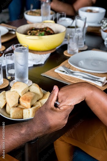 Black woman and Black man holding hands to pray before Sunday Soul Food Dinner, copy space