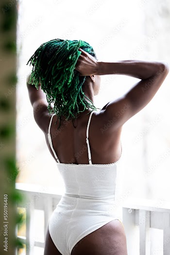 Black woman on patio playing with hair and enjoying nature
