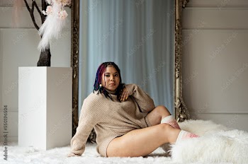 Black woman sitting on fur in front of a mirror