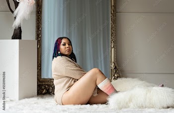 Black woman sitting on fur in front of a mirror